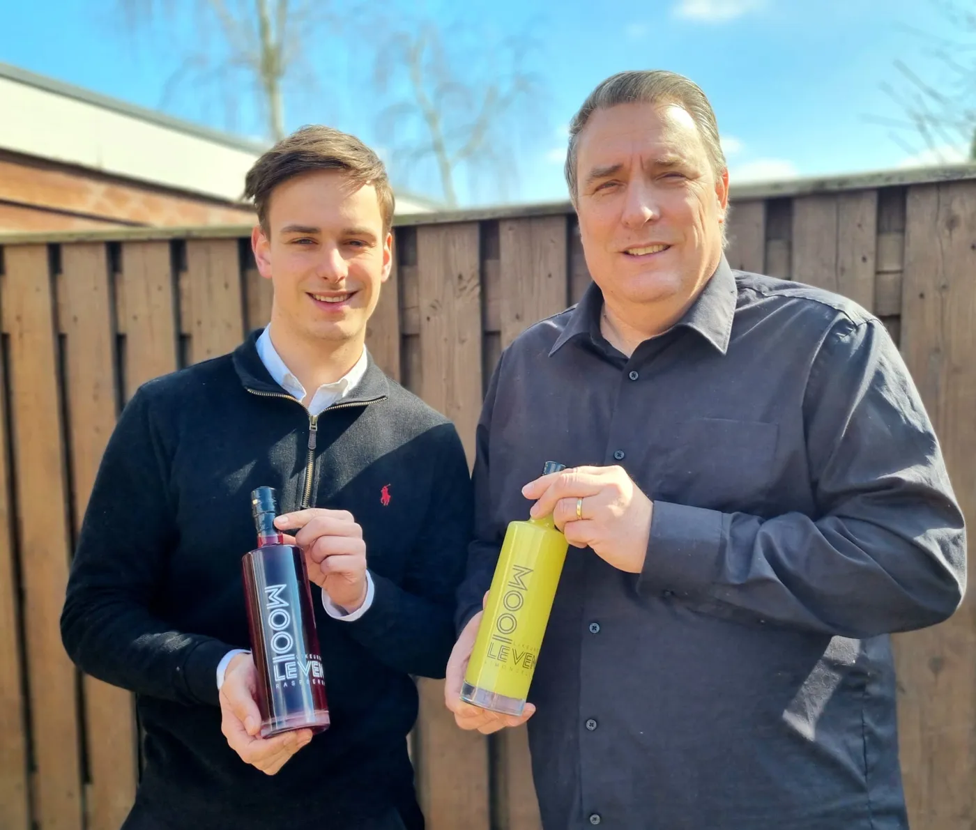 Thomas en Jos Huijbregts in de tuin, elk met een fles likeur